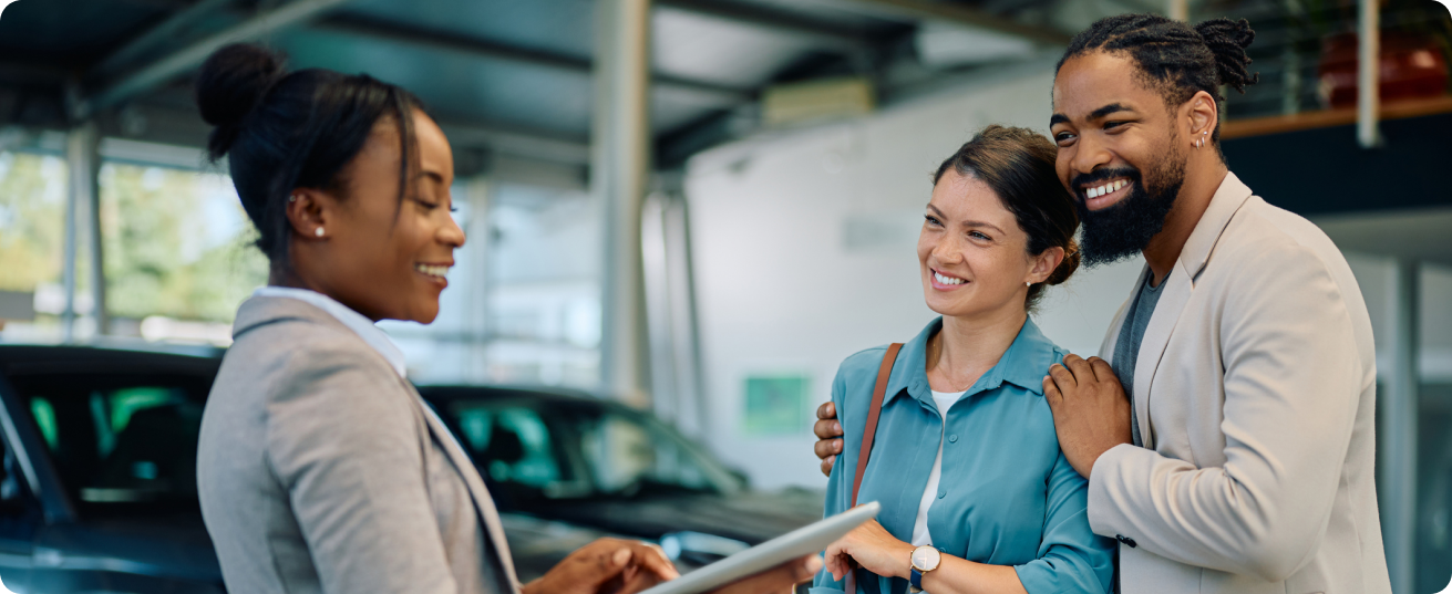 Couple in discussion with car sales manager in auto dealership
